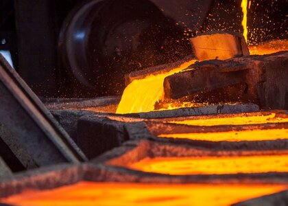 Image showing molten iron being cast into ingots. A carousel of metal ingots are being filled in turn by a steam of red-glowing iron.