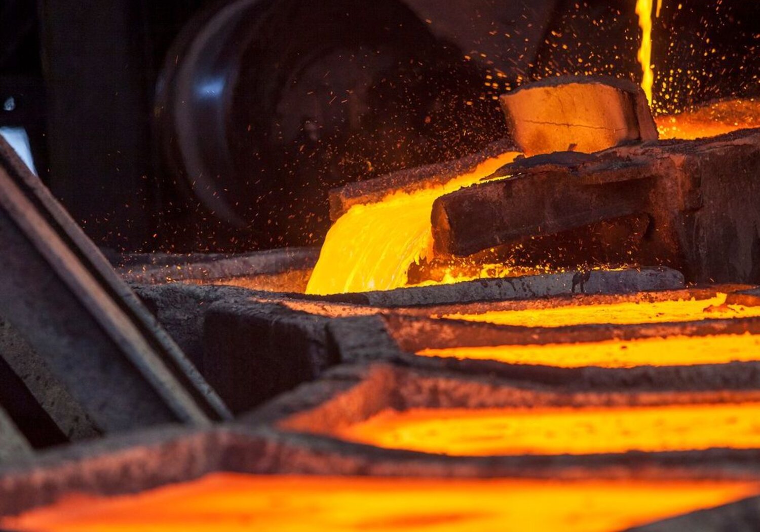 Image showing molten iron being cast into ingots. A carousel of metal ingots are being filled in turn by a steam of red-glowing iron.