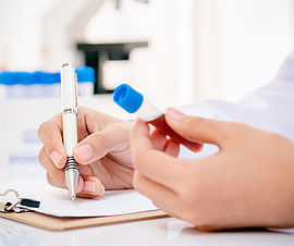 Image of a scientist recording blood anaysis results in laboratory