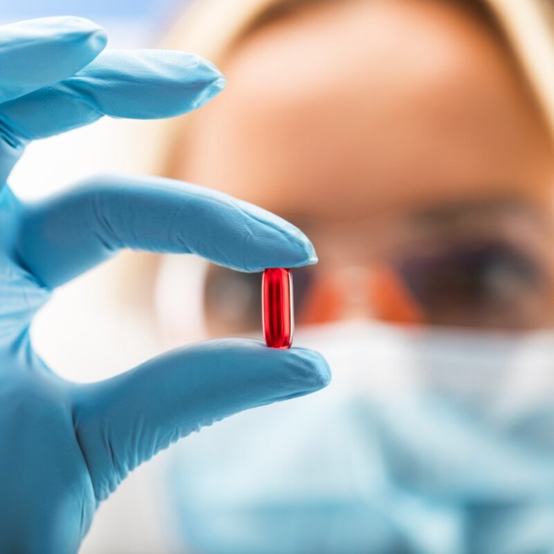 Image showing a scientist holding a red transparent pill