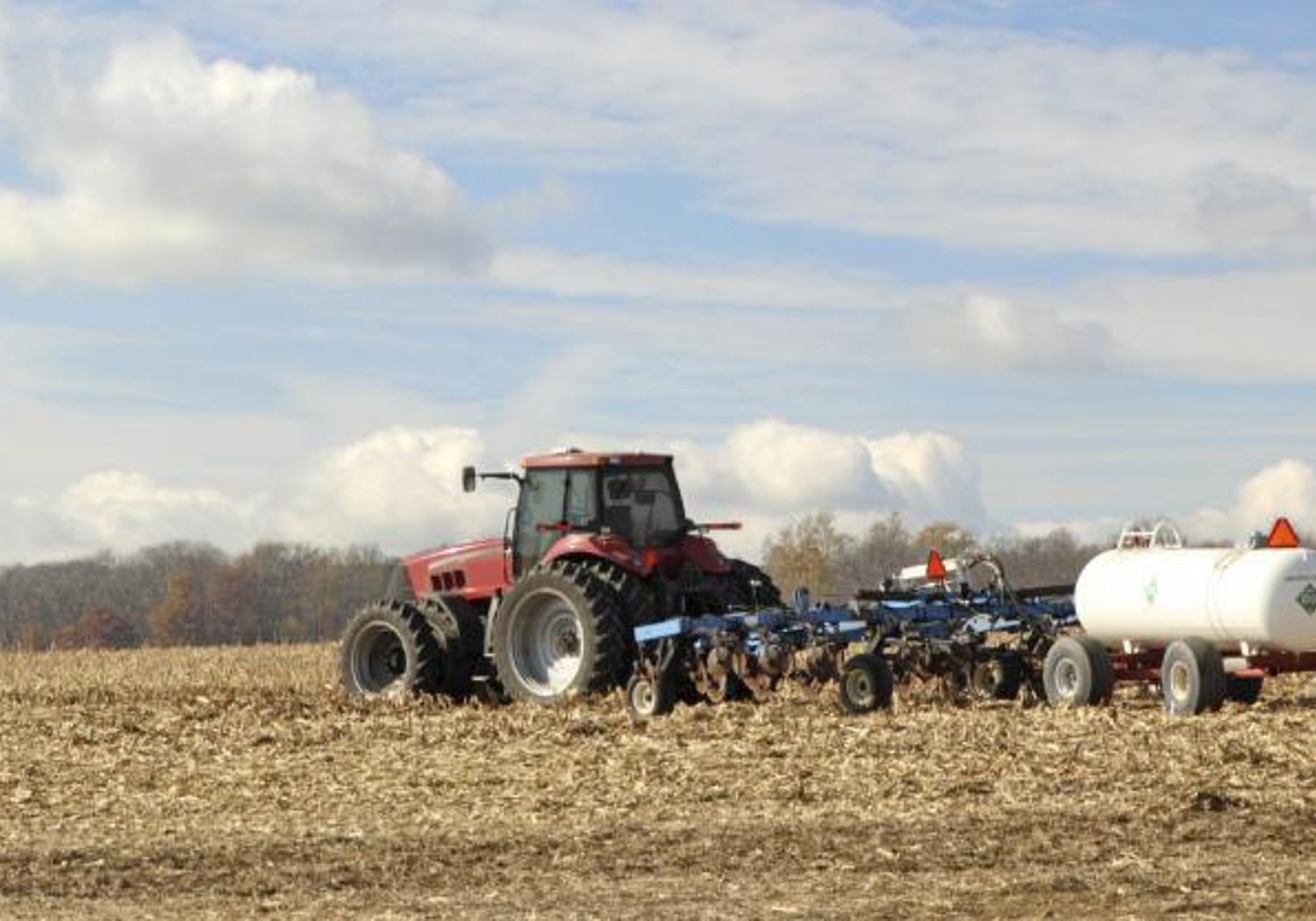 Image showing a tractor plowing and fertilising a field