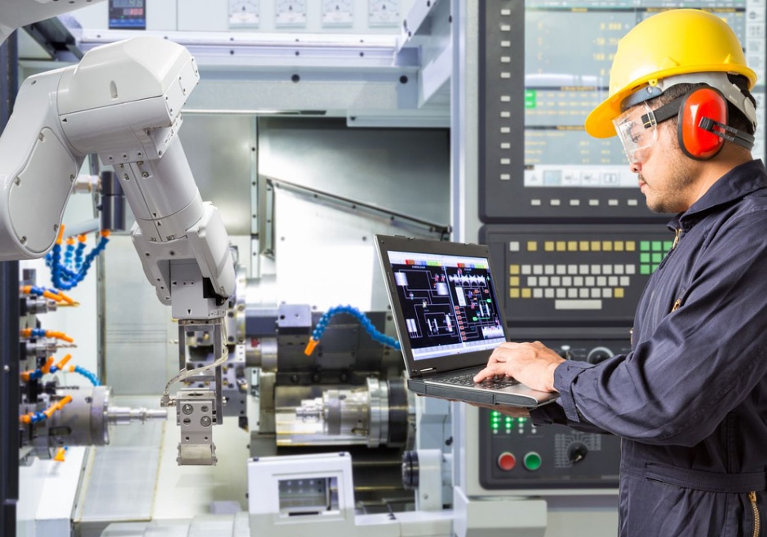 Image showing an engineer using a laptop to  control a robotic arm  performing maintenance