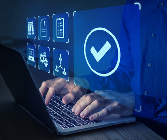 Close up of a man’s hands typing into the keyboard of a laptop. Superimposed is the screen he is working on showing various quality management icons