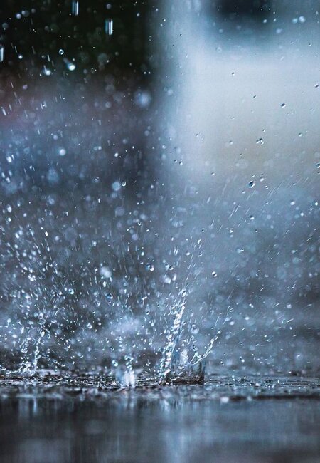 Image showing rain falling into a puddle, causing a splash of water