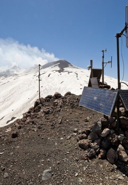 On the side of a smoking volcano a seismograph powered by solar cells is transmitting vibration data to headquarters