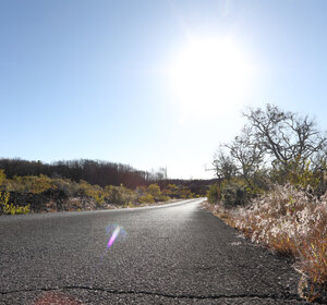 Image showing an empty road leading to a rising sun in the distance