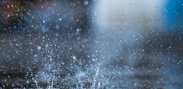 Image showing rain falling into a puddle, causing a splash of water