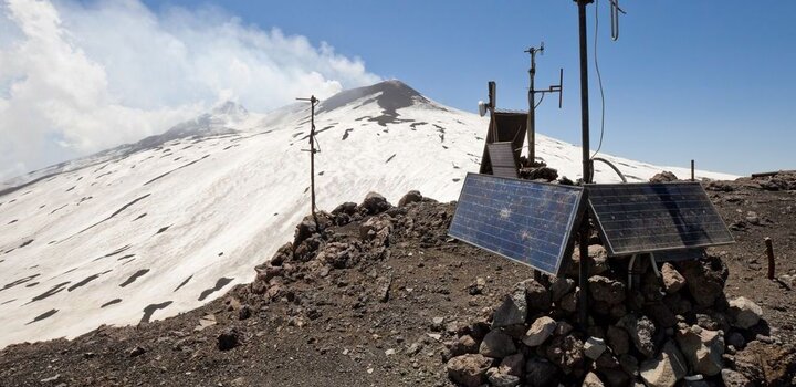 On the side of a smoking volcano a seismograph powered by solar cells is transmitting vibration data to headquarters