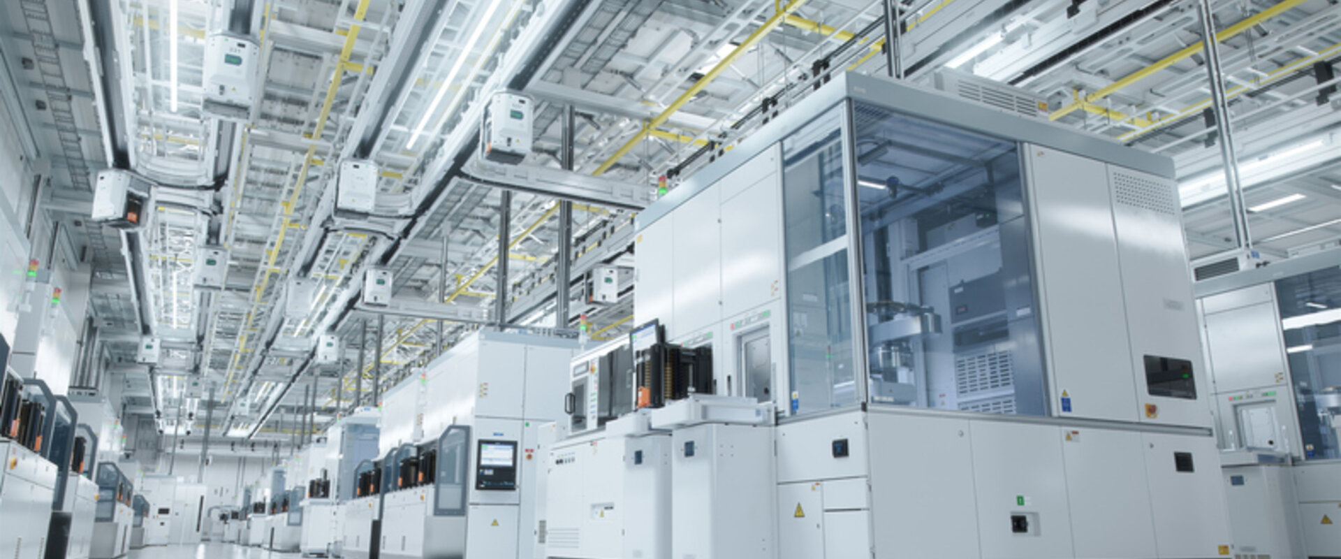 An advanced Semiconductor Production Cleanroom In a grey and sterile warehouse a series of enclosed modules producing semiconductors stretch off into the distance