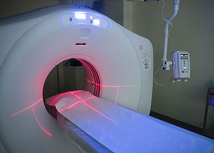 Large empty CT scanner in hospital showing bed and red lights Image showing a large empty CT scanner